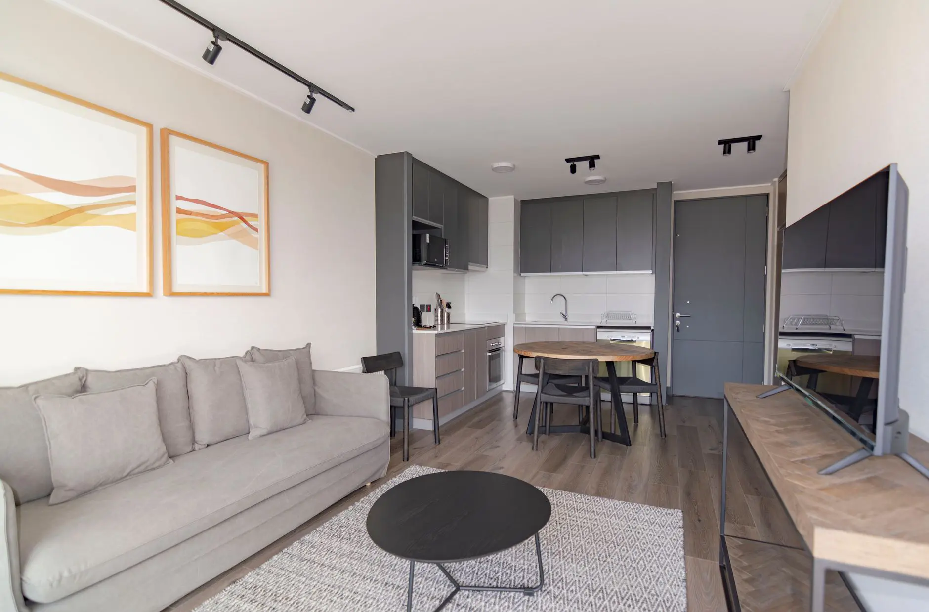 Sala de estar con sofá gris y cocina abierta en una vivienda