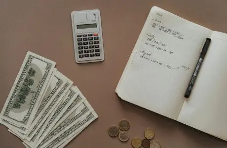 Calculadora, cuaderno y dólares sobre una mesa