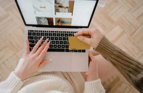 Persona usando una computadora portátil junto a una tarjeta bancaria