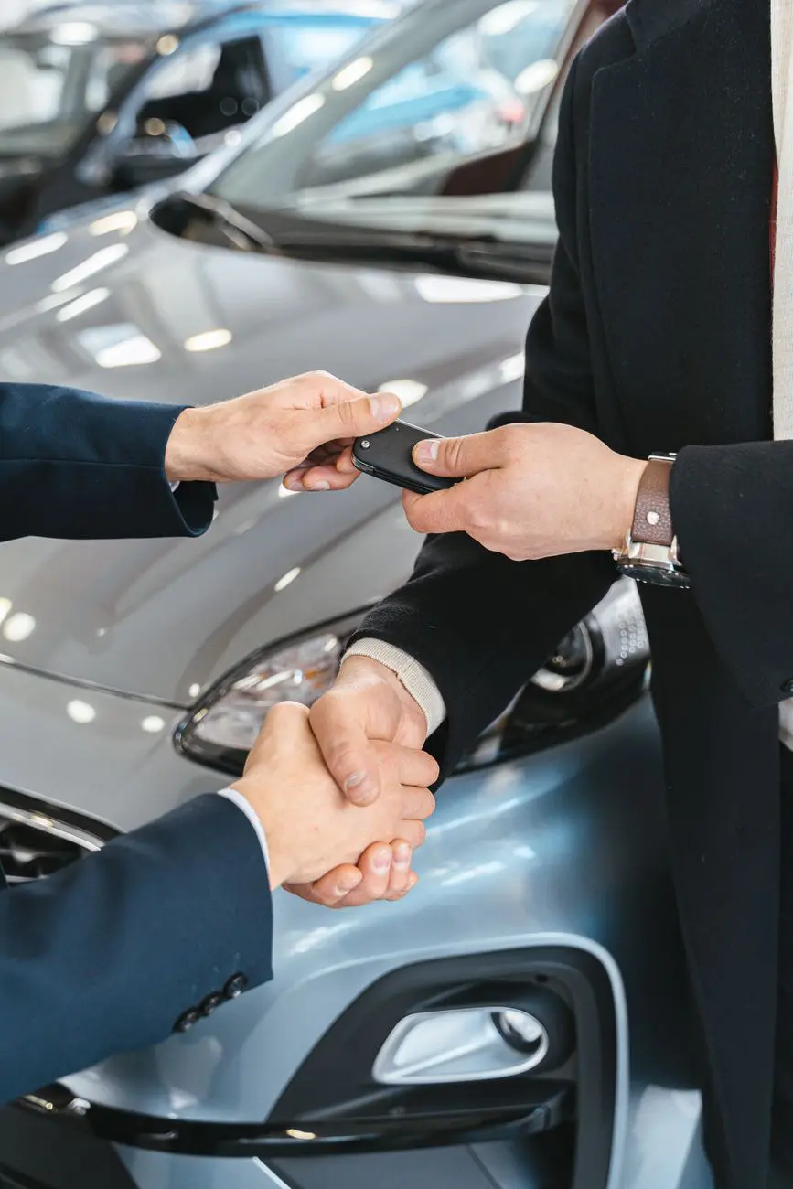 Entrega de llaves y apretón de manos junto a un automóvil