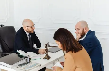 Tres personas revisando documentos durante una consulta profesional