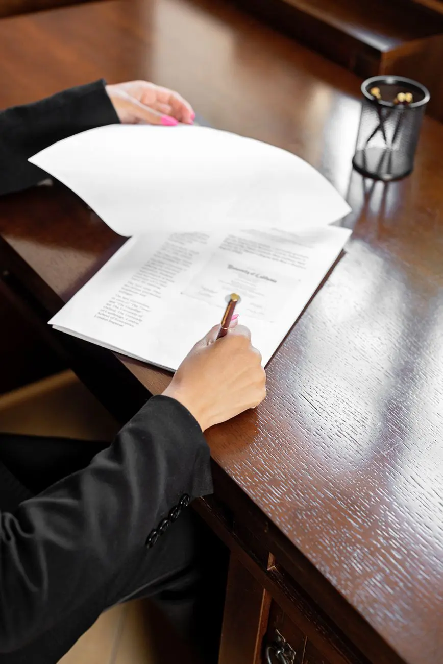 Persona firmando un documento sobre una mesa