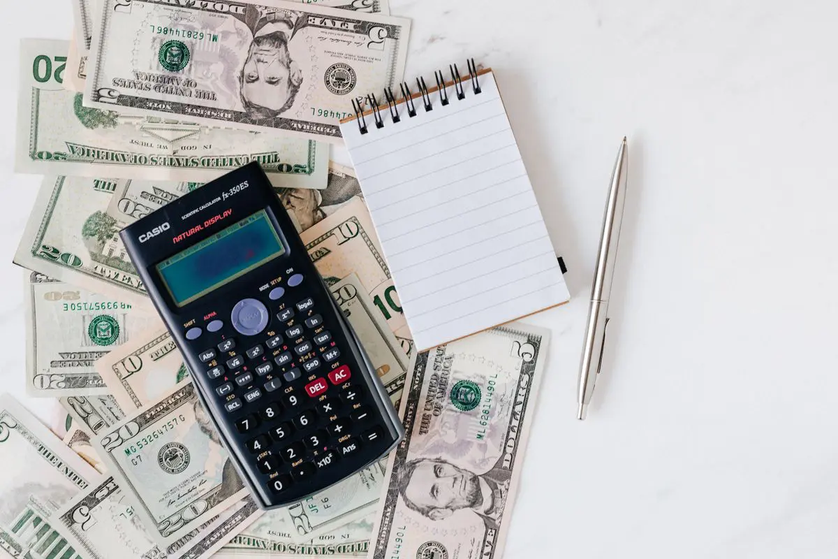 Calculadora, libreta y dólares para revisar un presupuesto