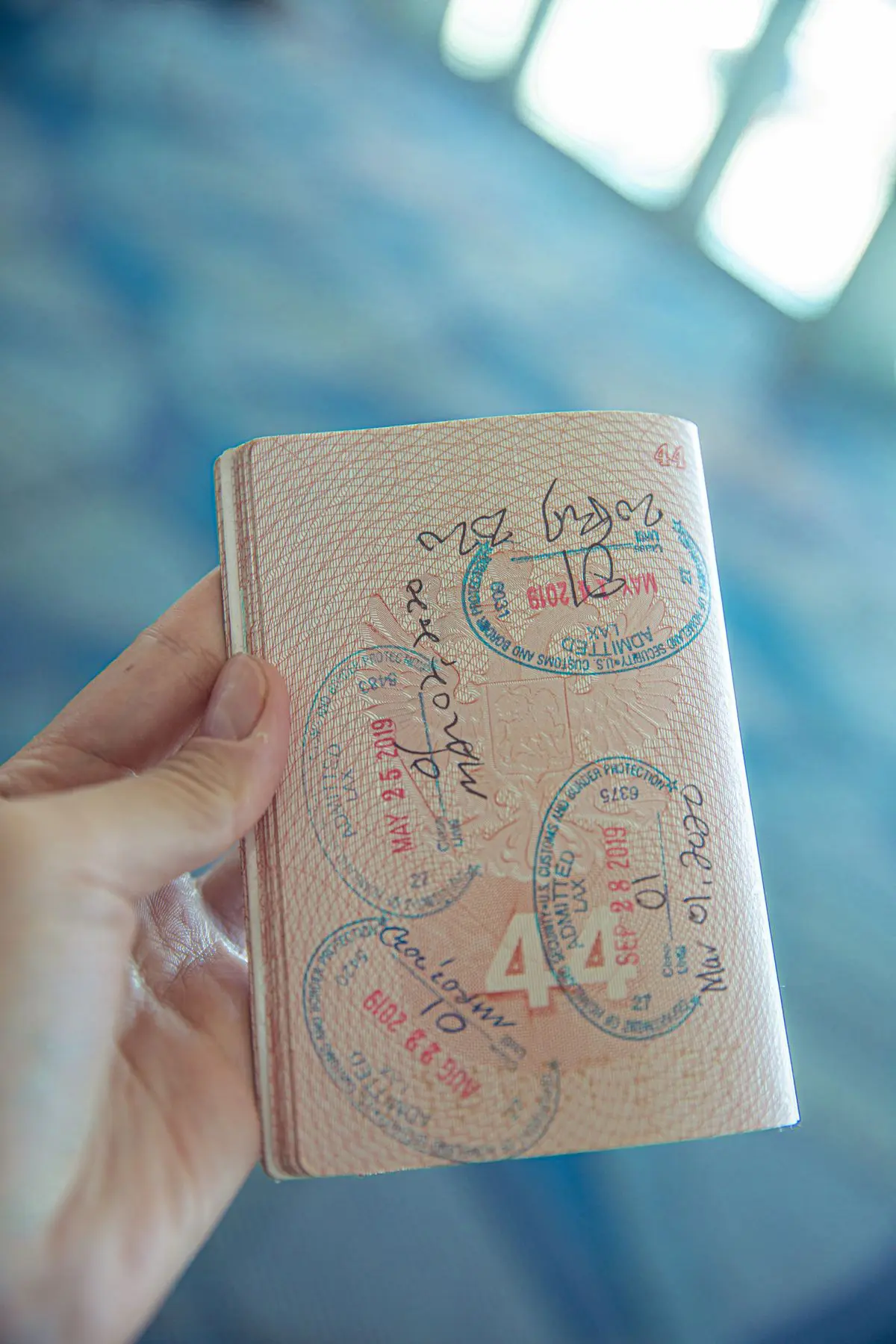 Mano sosteniendo un pasaporte abierto con sellos de entrada