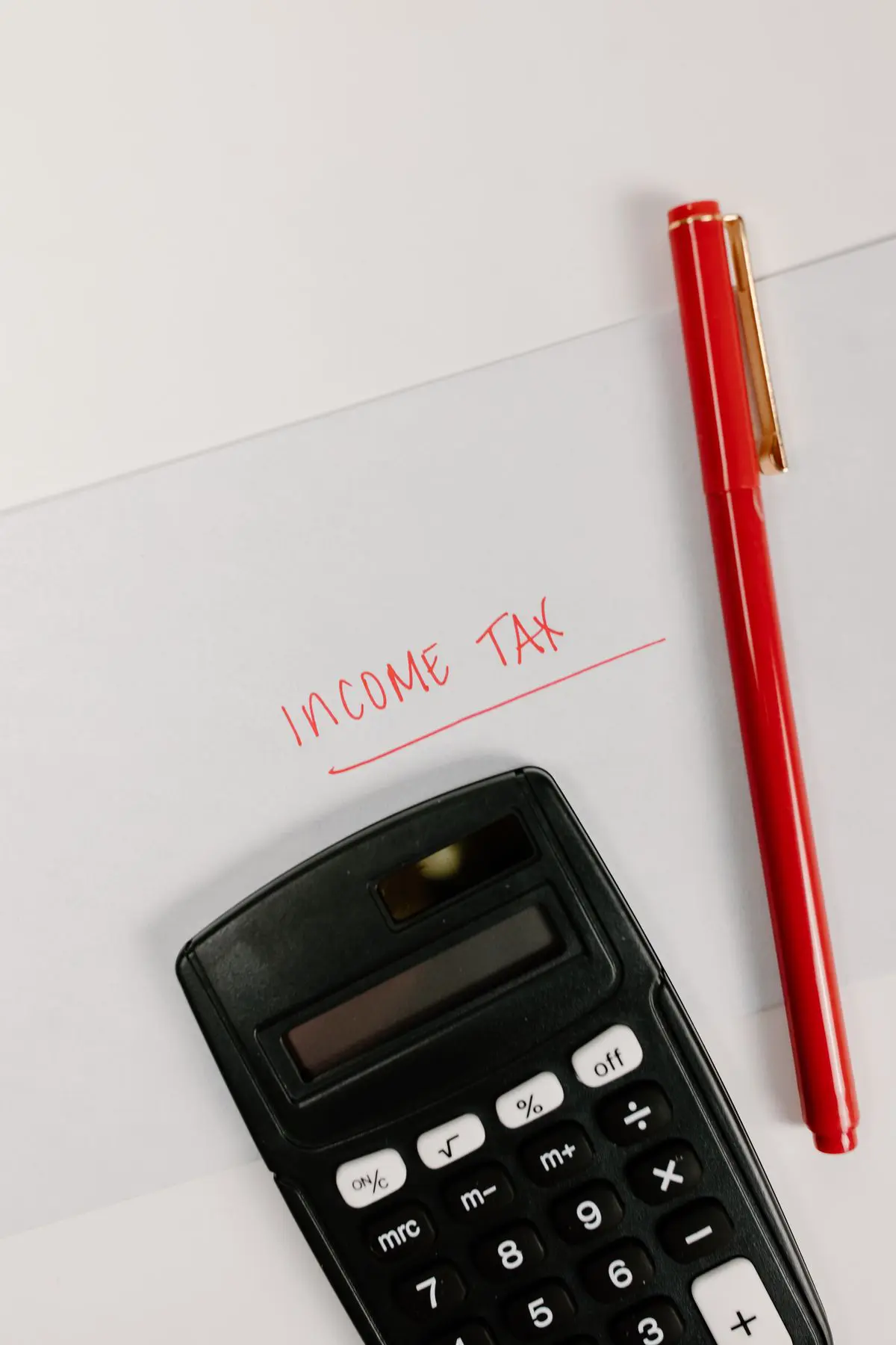 Calculadora y bolígrafo junto a una nota sobre impuestos sobre la renta