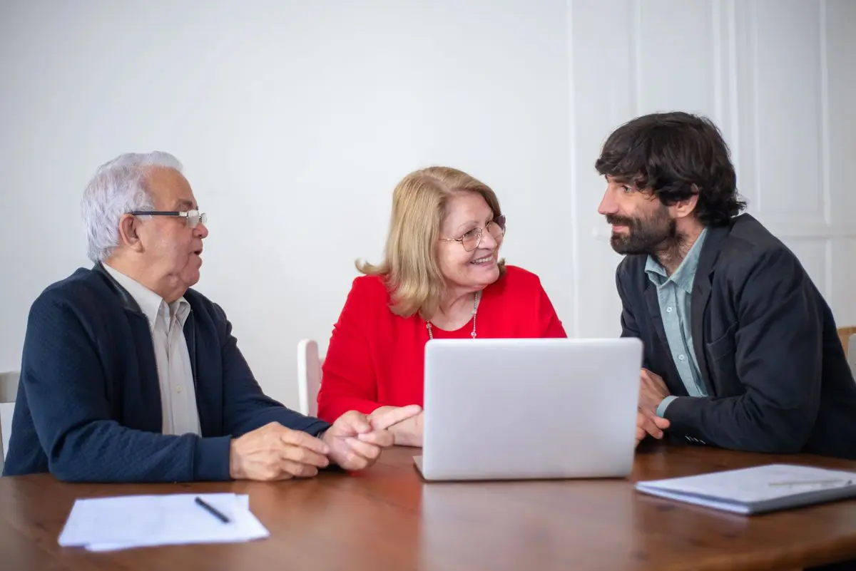 Pareja conversando con un asesor ante una computadora y documentos