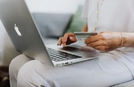 Persona con una tarjeta bancaria usando una computadora en casa
