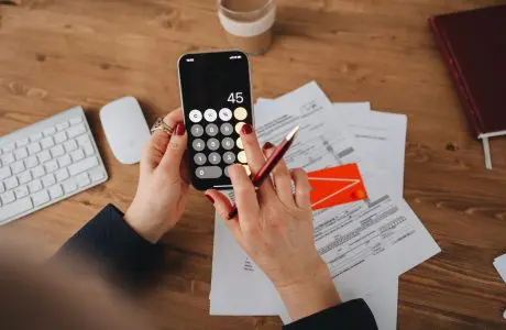 Manos con un teléfono y documentos para comparar gastos bancarios