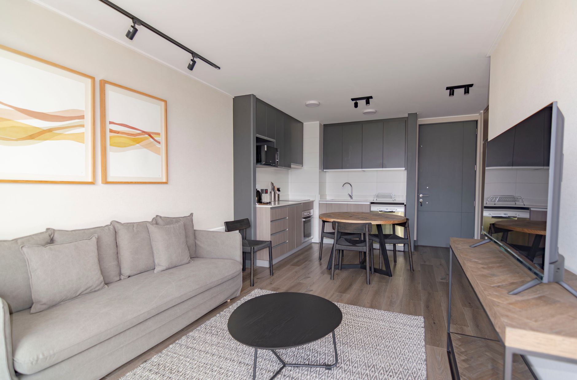 Sala de estar con sofá gris y cocina abierta en una vivienda