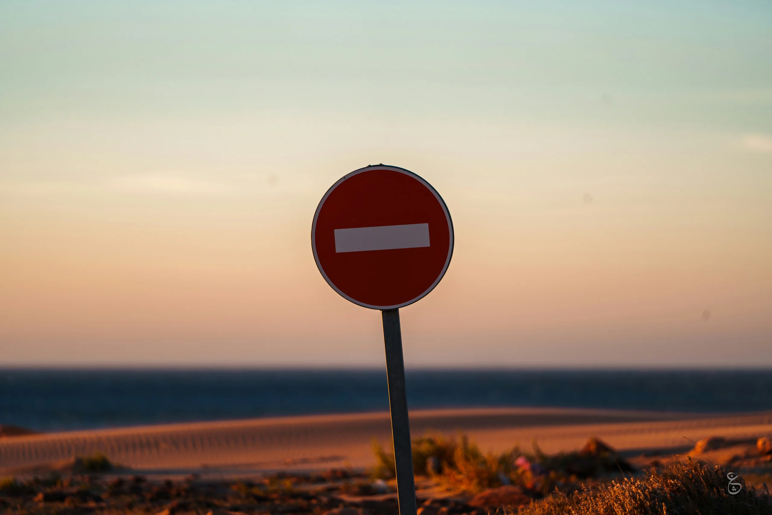 Foto por <a href="https://unsplash.com/@theemanofoth?utm_source=unsplash&utm_medium=referral&utm_content=creditCopyText">Othman Alghanmi</a> on <a href="https://unsplash.com/photos/a-red-street-sign-sitting-on-the-side-of-a-road-E9ii3nDDd8Q?utm_source=unsplash&utm_medium=referral&utm_content=creditCopyText">Unsplash</a>