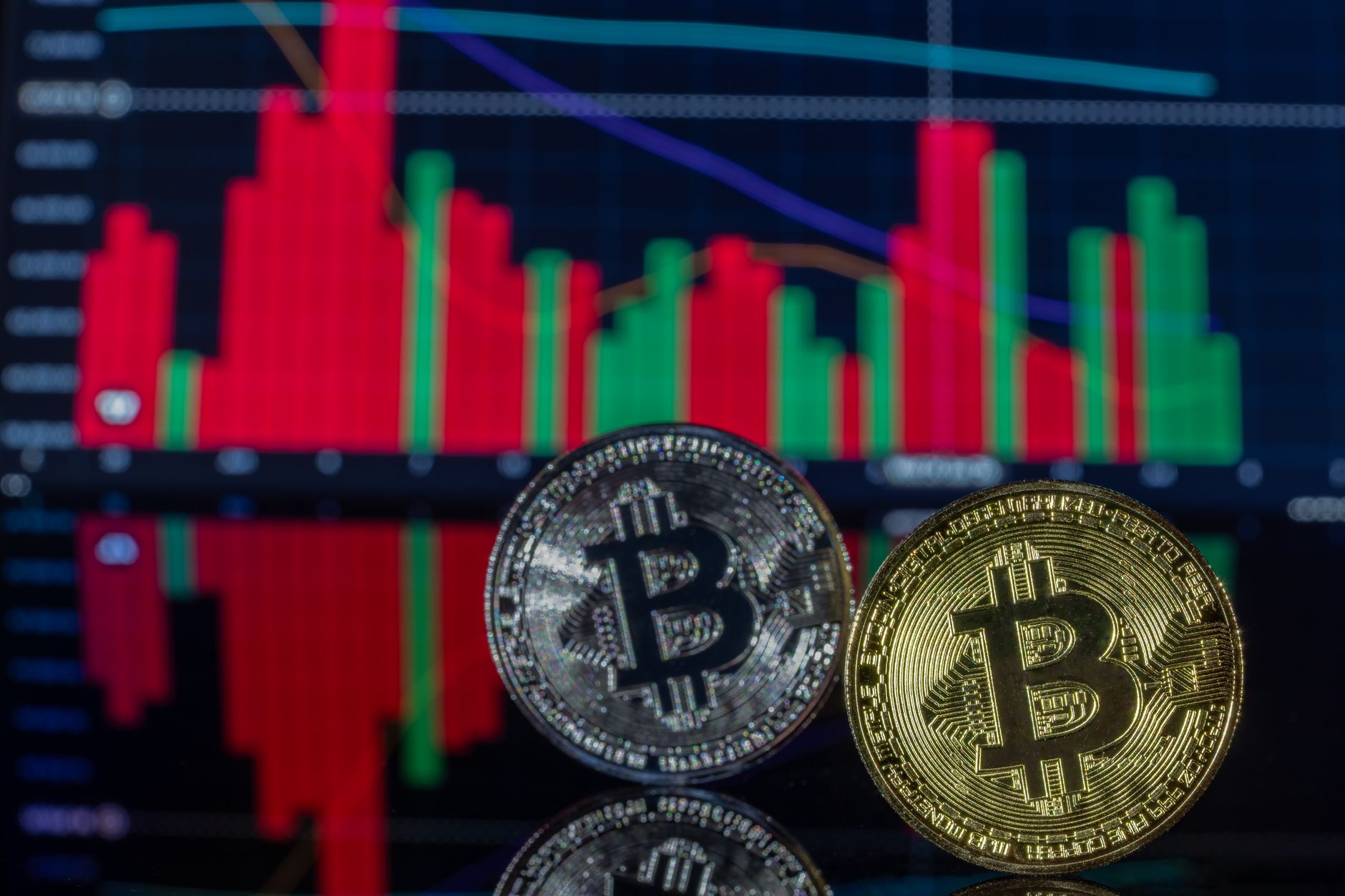 Monedas decorativas de Bitcoin delante de un gráfico financiero