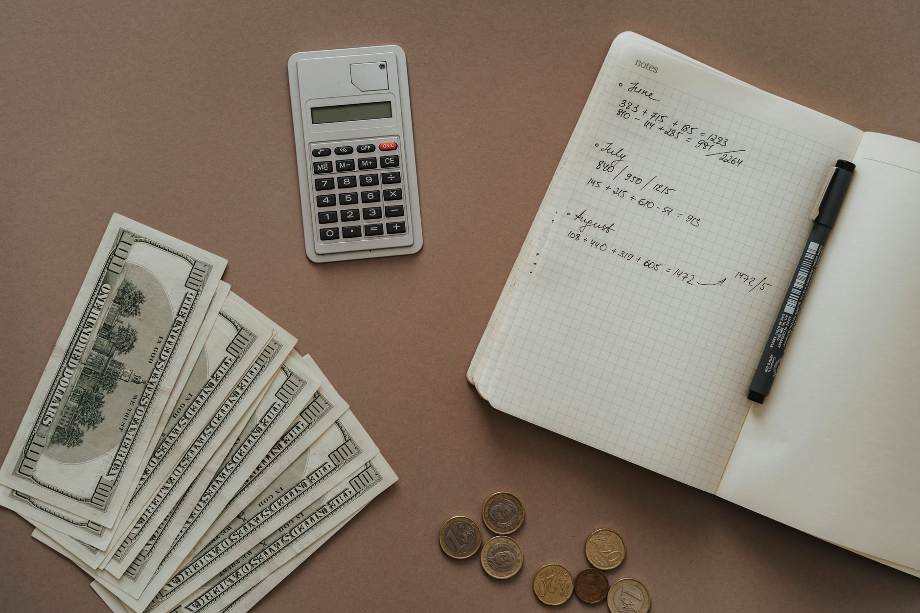 Calculadora, cuaderno y dólares sobre una mesa