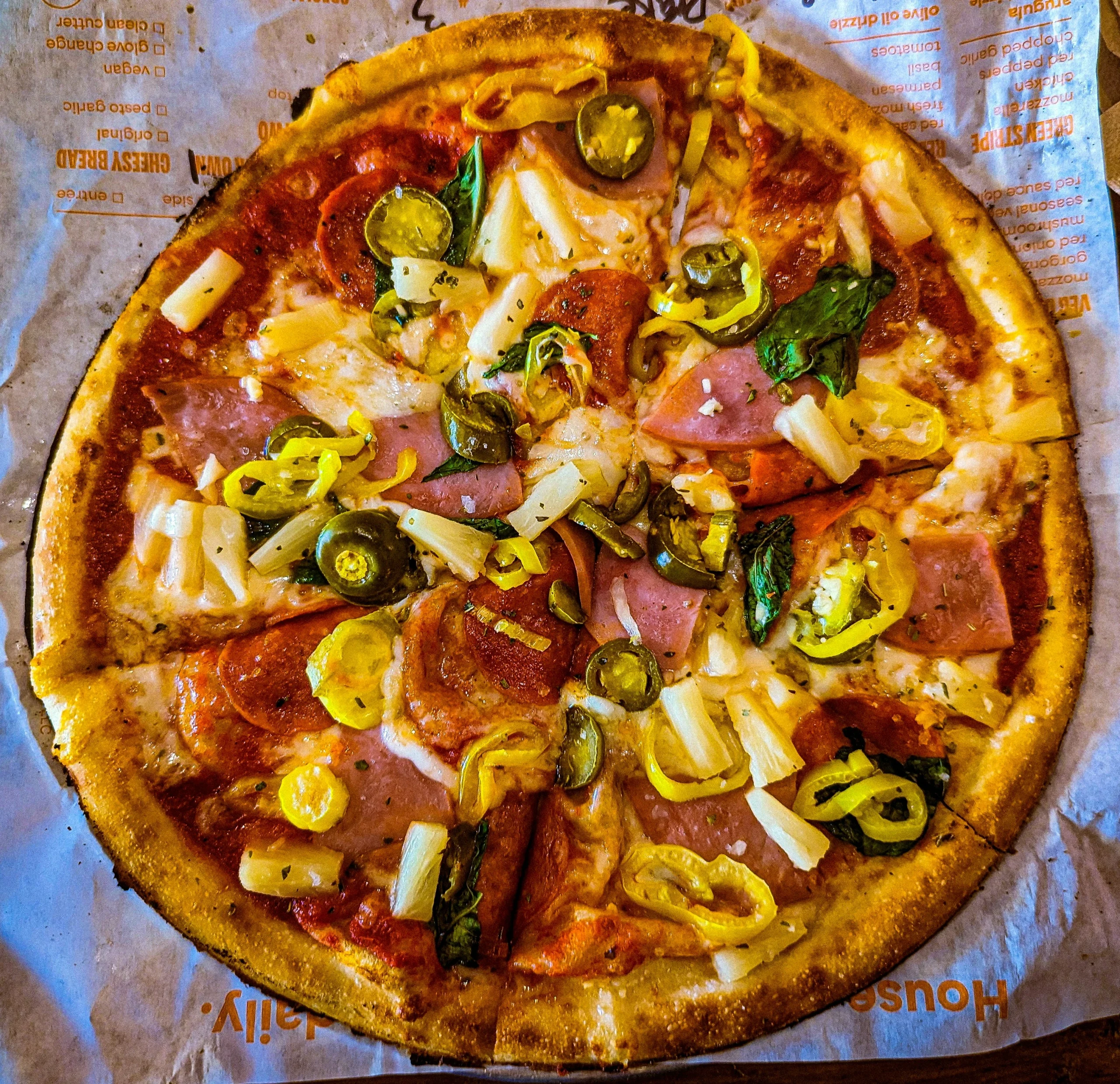 Foto por <a href="https://unsplash.com/@thesupremechips?utm_source=unsplash&utm_medium=referral&utm_content=creditCopyText">Drake Whitney</a> on <a href="https://unsplash.com/photos/a-pizza-sitting-on-top-of-a-piece-of-paper-pWqMo3bhv3A?utm_source=unsplash&utm_medium=referral&utm_content=creditCopyText">Unsplash</a>