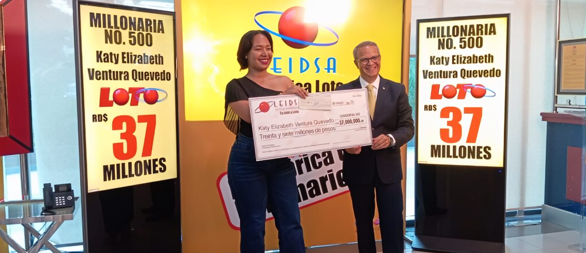 Katy Elizabeth Ventura Quevedo sosteniendo el premio de la loteria junto a presentador de programa