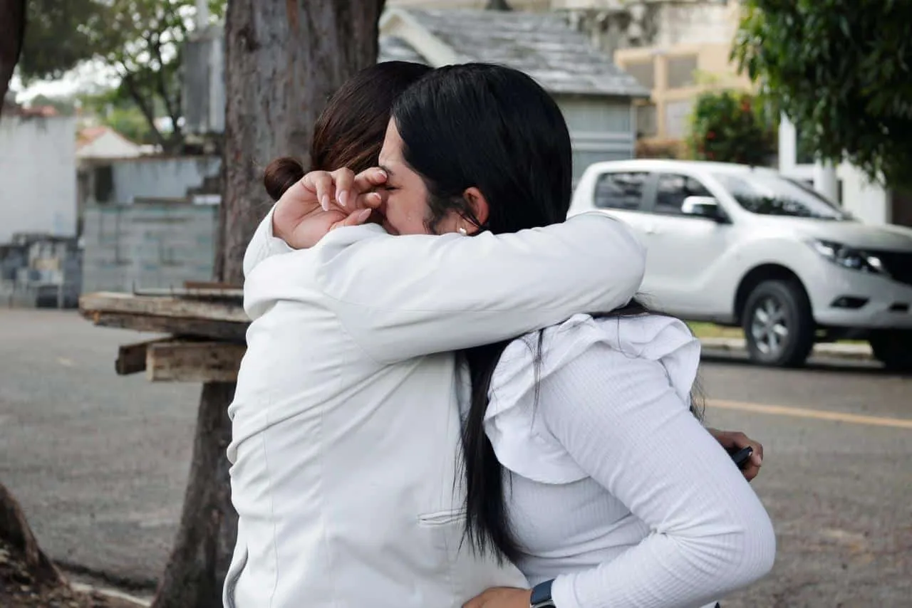 Ámbar Moronta, hermana de Esmeralda Moronta de los Santos, rompe en llanto mientras abraza a un familiar en las afueras del Inacif, en medio de la espera por la entrega del cuerpo