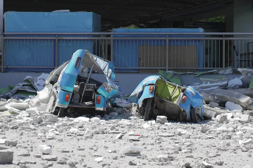 Vehículos dañados por los cascotes de un edificio en la ciudad filipina de General Santos, este lunes