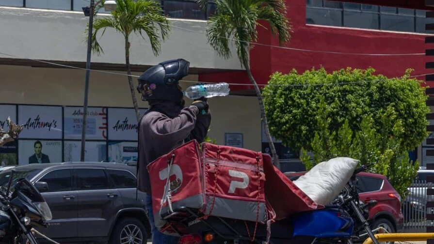 Un motorista se hidrata para mitigar el calor en una calle del Gran Santo Domingo. (JOLIVER BRITO/DIARIO LIBRE)