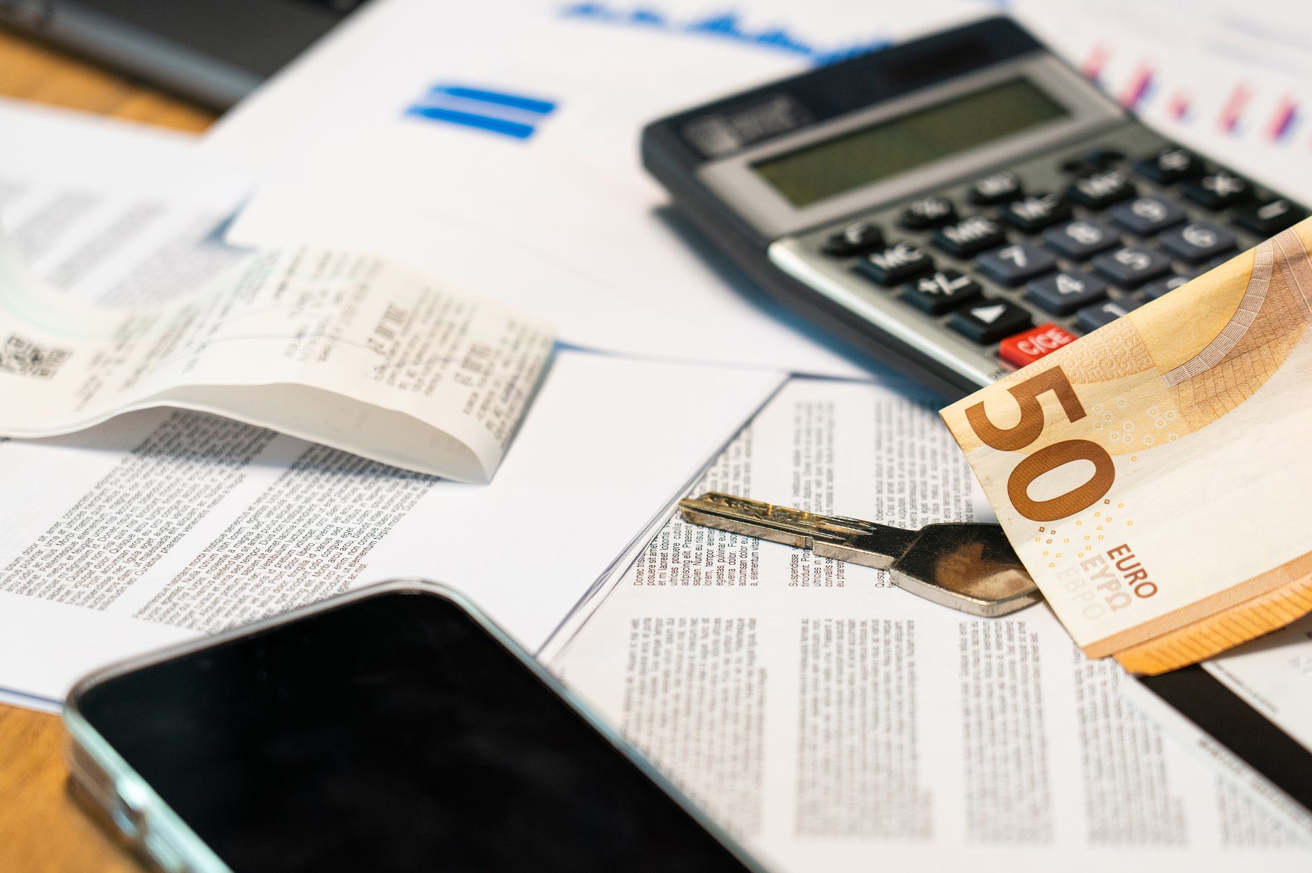 Documentos financieros, calculadora y teléfono sobre una mesa