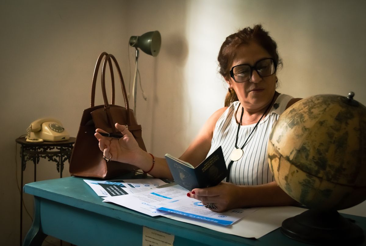 Mujer consultando un pasaporte en su escritorio