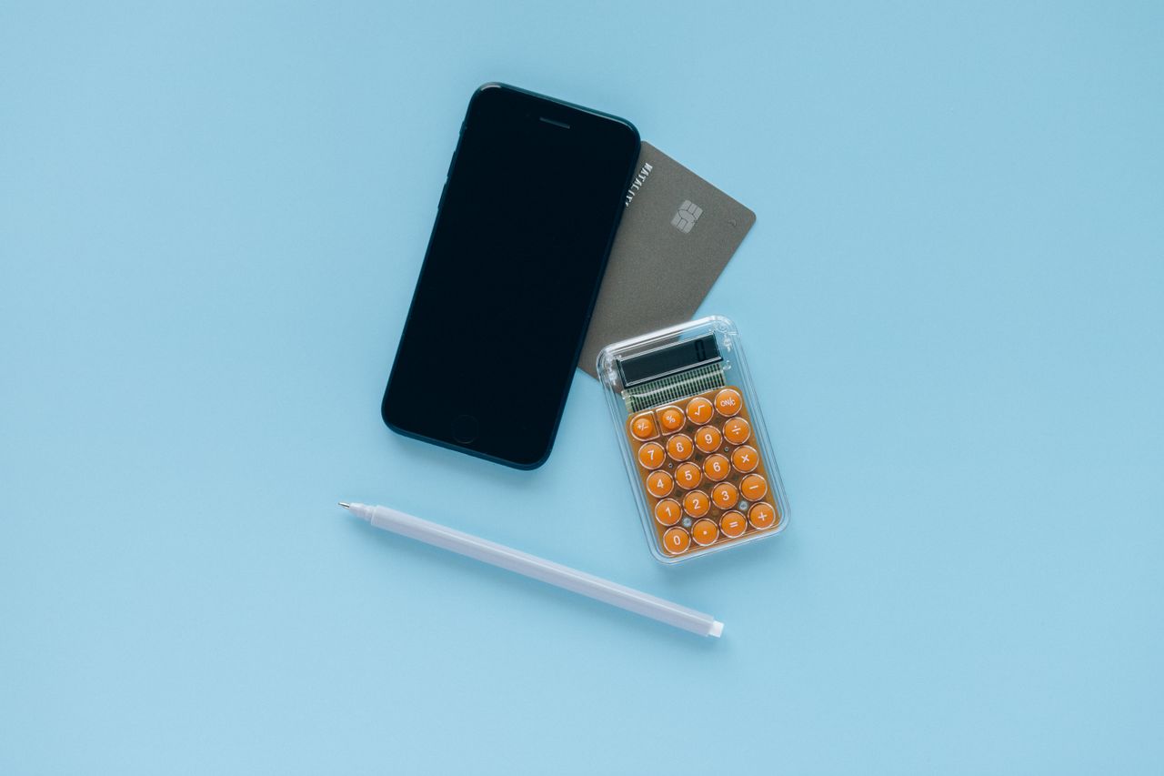Teléfono, tarjeta bancaria y calculadora sobre una mesa azul