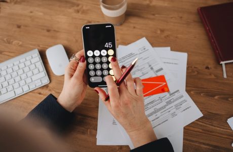 Manos con un teléfono y documentos para comparar gastos bancarios
