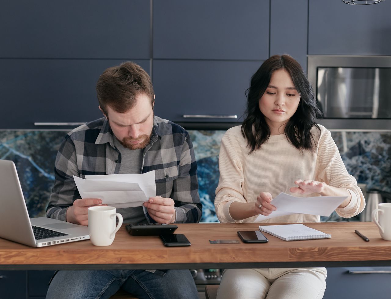 Dos personas revisando papeles y una computadora en una mesa