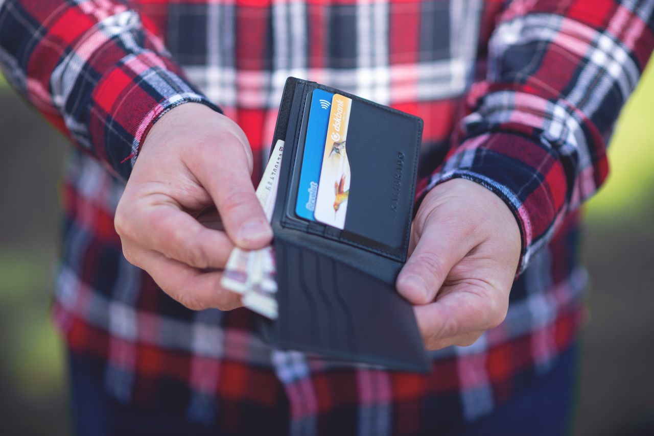 Manos sosteniendo una cartera abierta con tarjetas