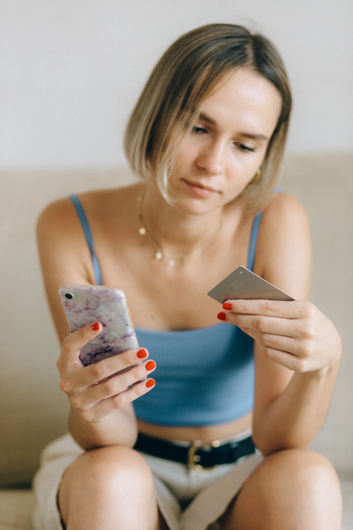 Mujer mirando su teléfono con una tarjeta en la mano